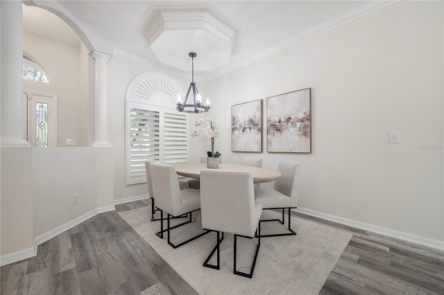 dining area with ornate columns, ornamental molding, an inviting chandelier, and hardwood / wood-style floors