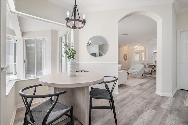 dining space with crown molding, light hardwood / wood-style flooring, and a chandelier