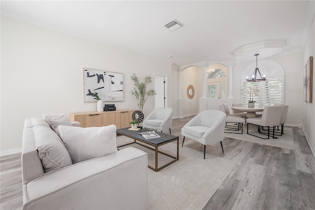 living room with crown molding, light hardwood / wood-style flooring, and an inviting chandelier