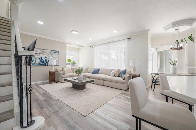 living room with a notable chandelier, a textured ceiling, light hardwood / wood-style flooring, and ornamental molding