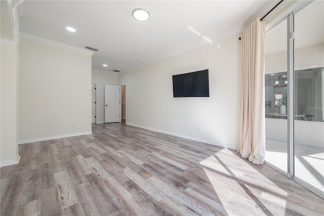 spare room featuring crown molding and light hardwood / wood-style floors