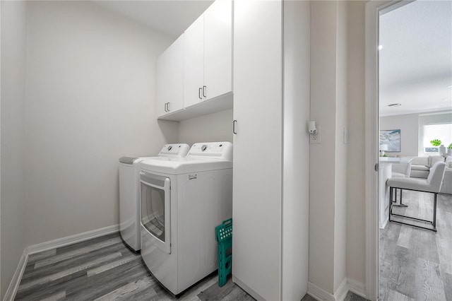 washroom with separate washer and dryer, cabinets, and light wood-type flooring