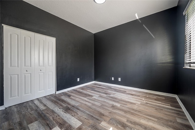 unfurnished bedroom with a closet, vaulted ceiling, wood-type flooring, and a textured ceiling