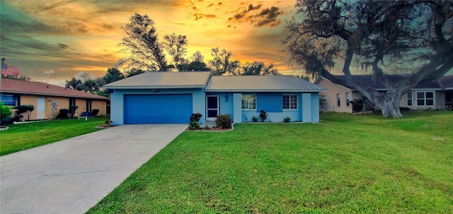 single story home featuring a garage and a lawn