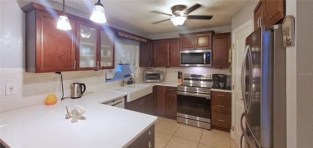 kitchen with appliances with stainless steel finishes, sink, backsplash, decorative light fixtures, and light tile patterned floors