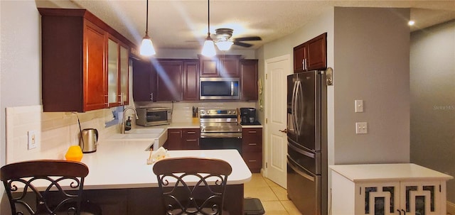 kitchen featuring backsplash, stainless steel appliances, decorative light fixtures, and kitchen peninsula