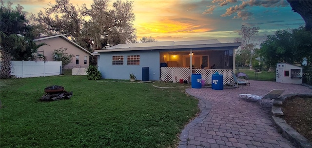 back house at dusk featuring a yard and a fire pit