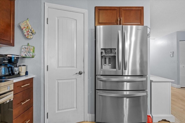 1467 Monte St, Port Charlotte, FL 33952 - kitchen with stainless steel refrigerator with ice dispenser, light countertops, brown cabinetry, and light wood-style floors