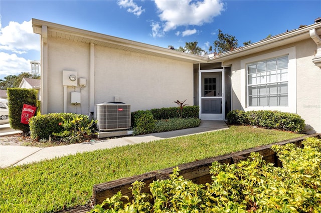 doorway to property featuring central AC unit and a lawn