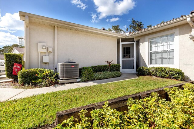 4234 Chesterfield Cir, Palm Harbor, FL 34683 - view of exterior entry featuring central AC and stucco siding