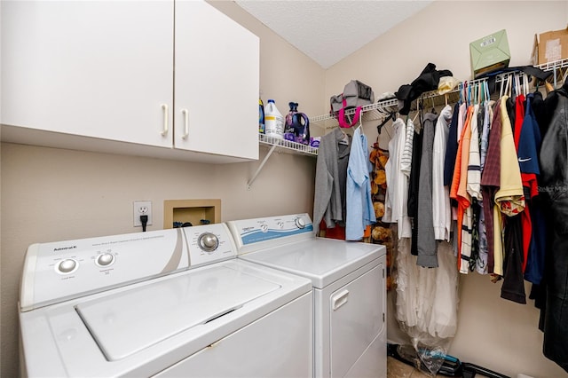 clothes washing area with cabinets, independent washer and dryer, and a textured ceiling