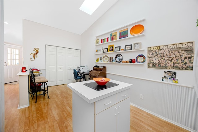 kitchen with vaulted ceiling, light hardwood / wood-style flooring, white cabinetry, and a center island