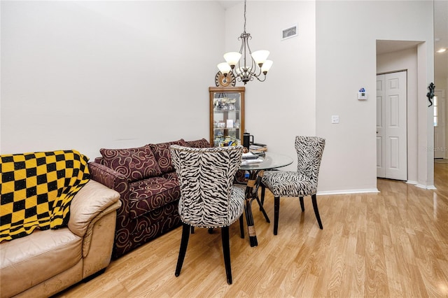 4234 Chesterfield Cir, Palm Harbor, FL 34683 - dining room featuring a chandelier, light wood-style flooring, a high ceiling, and baseboards