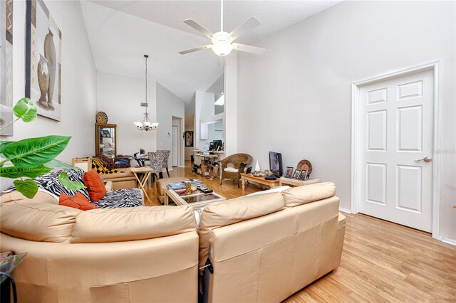 living room featuring high vaulted ceiling, light hardwood / wood-style flooring, and ceiling fan with notable chandelier