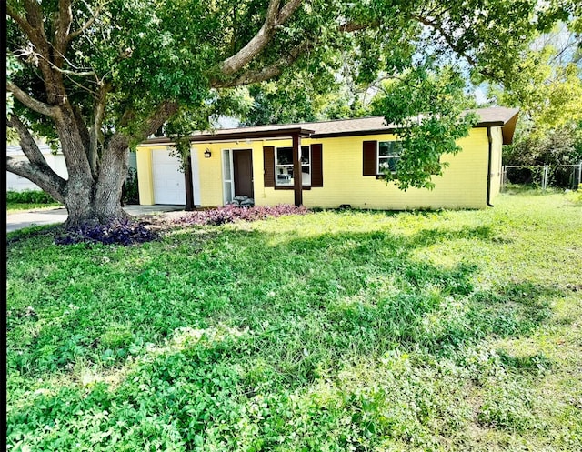 single story home featuring driveway, fence, a front yard, a garage, and brick siding