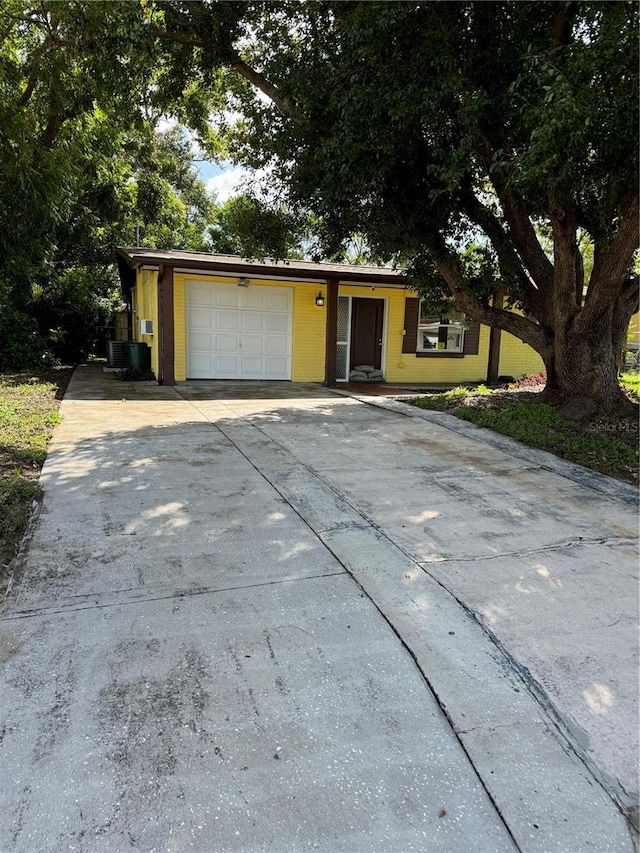 view of front of house with concrete driveway, an attached garage, and central AC unit