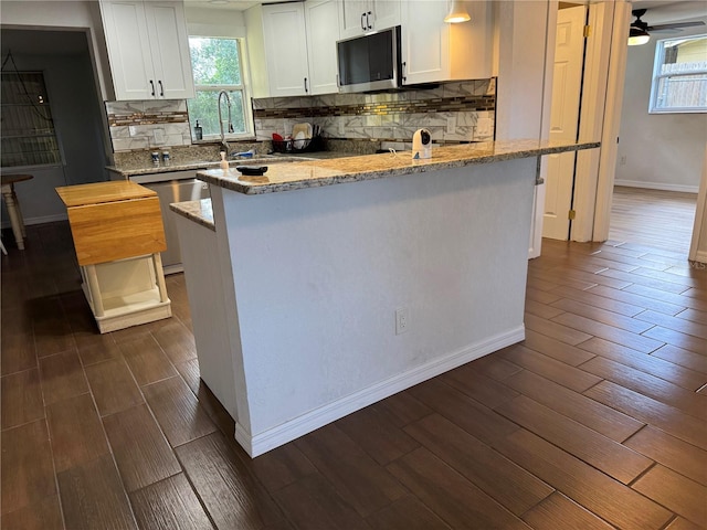 kitchen with white cabinets, appliances with stainless steel finishes, dark wood-type flooring, and a sink