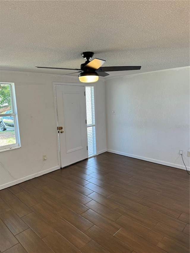 empty room featuring ceiling fan, a textured ceiling, and dark wood-type flooring