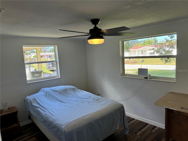 bedroom featuring ceiling fan, dark hardwood / wood-style flooring, a textured ceiling, and multiple windows