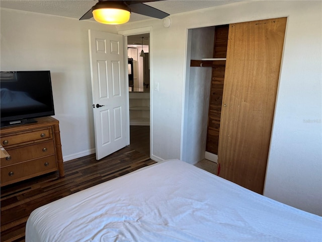 bedroom with ceiling fan, dark hardwood / wood-style floors, a textured ceiling, and a closet