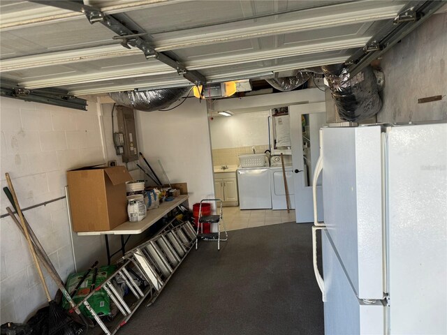 garage featuring washing machine and clothes dryer and white refrigerator