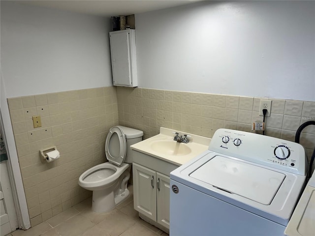 bathroom featuring vanity, tile patterned flooring, toilet, tile walls, and washer / dryer