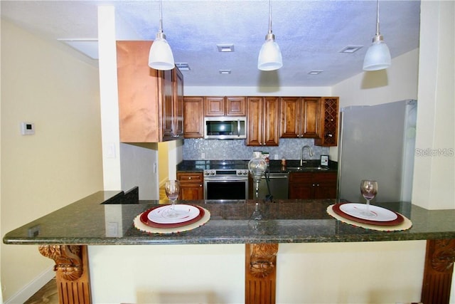 kitchen featuring sink, pendant lighting, stainless steel appliances, and backsplash