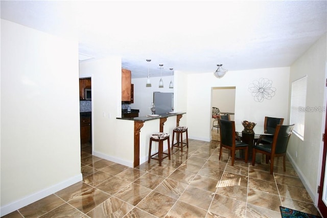 kitchen featuring a kitchen breakfast bar, kitchen peninsula, decorative light fixtures, and stainless steel appliances