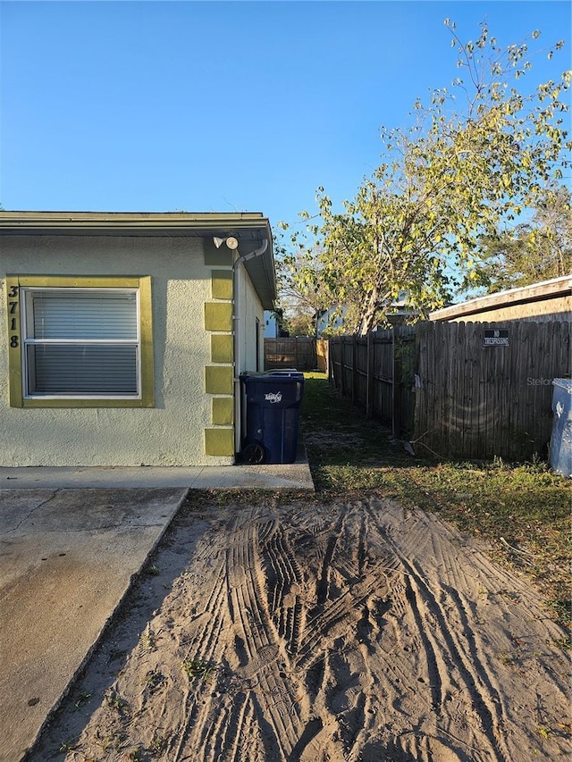 view of side of property featuring stucco siding and fence