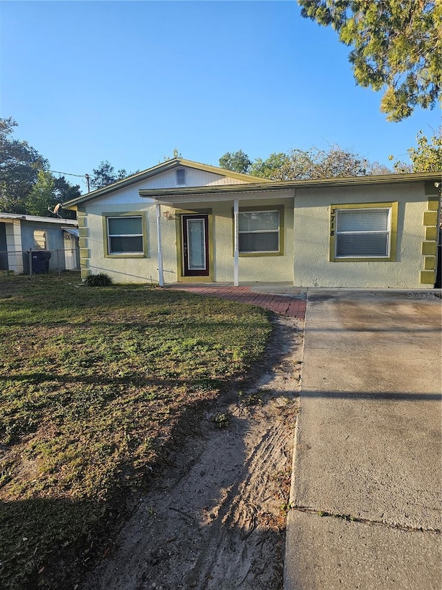 view of front of house with a porch, a front lawn, and stucco siding