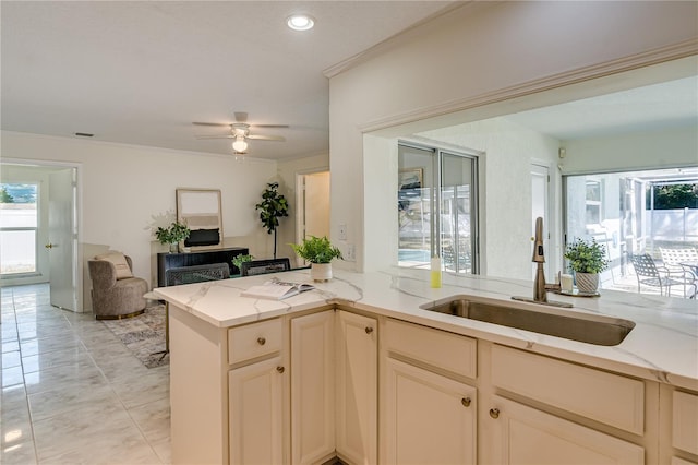 kitchen featuring kitchen peninsula, sink, crown molding, light stone counters, and ceiling fan