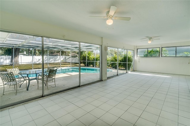 unfurnished sunroom with ceiling fan, plenty of natural light, and a swimming pool