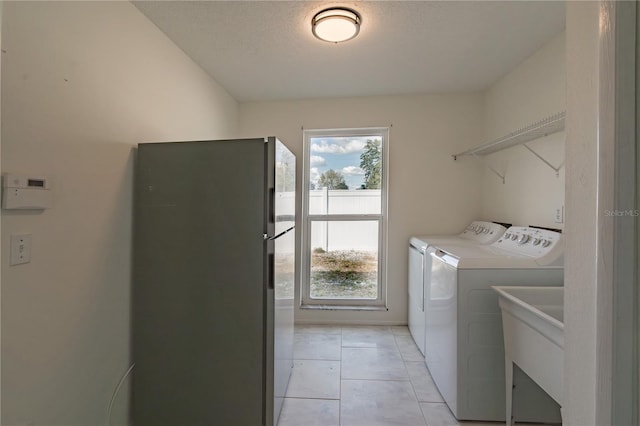 washroom featuring a textured ceiling, sink, washing machine and dryer, and light tile patterned floors