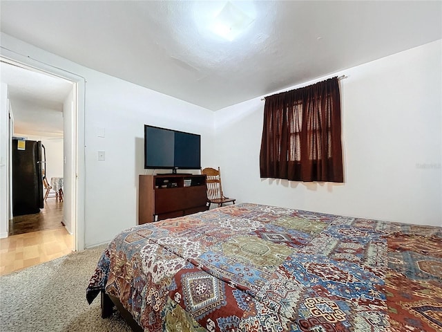 bedroom featuring carpet and black refrigerator