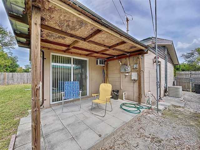 view of patio with central air condition unit and a wall mounted air conditioner