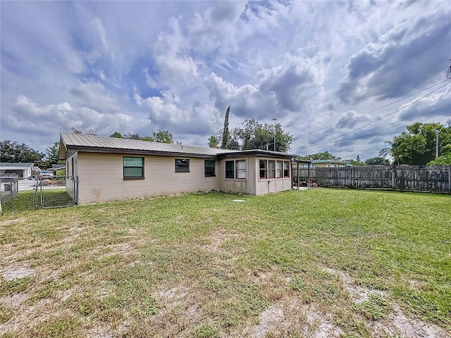 rear view of property featuring a yard and a sunroom