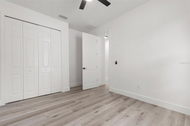 unfurnished bedroom featuring ceiling fan, a closet, and light wood-type flooring