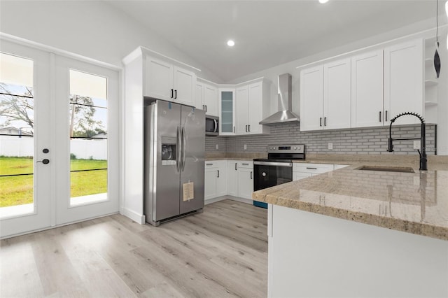 kitchen featuring white cabinets, wall chimney exhaust hood, sink, and appliances with stainless steel finishes