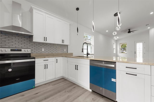 kitchen featuring white cabinetry, sink, appliances with stainless steel finishes, hanging light fixtures, and wall chimney range hood