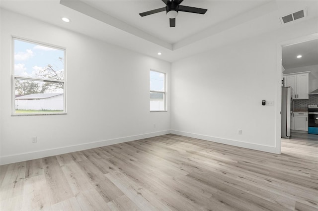 unfurnished room with light wood-type flooring, a wealth of natural light, and ceiling fan