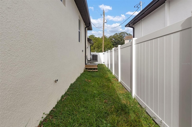 view of side of property with central AC unit and a yard