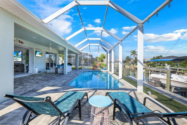 view of pool featuring a patio, a lanai, ceiling fan, a dock, and an outdoor living space