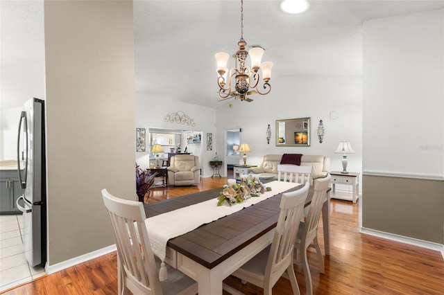 dining area featuring vaulted ceiling, a notable chandelier, and hardwood / wood-style flooring