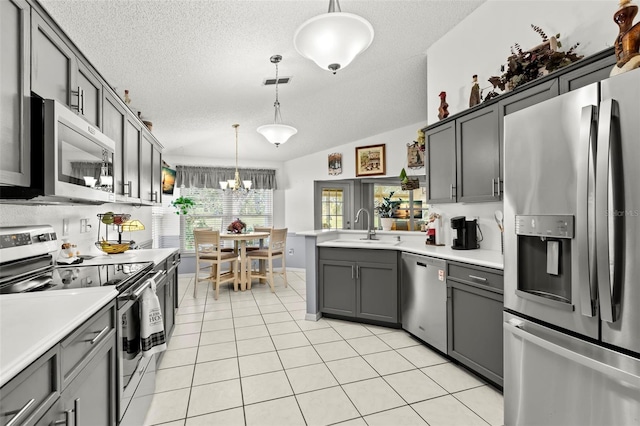 kitchen with sink, vaulted ceiling, appliances with stainless steel finishes, and decorative light fixtures