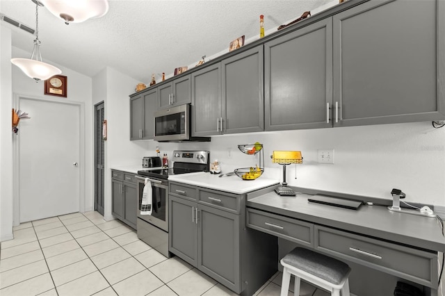 kitchen featuring light tile patterned floors, a textured ceiling, gray cabinetry, decorative light fixtures, and stainless steel appliances