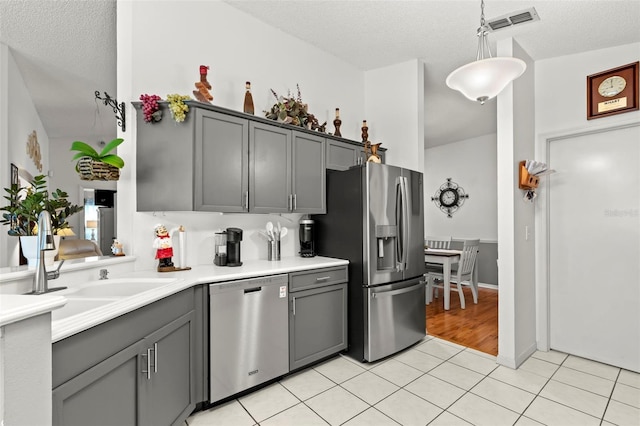 kitchen featuring gray cabinetry, pendant lighting, light tile patterned floors, appliances with stainless steel finishes, and a textured ceiling