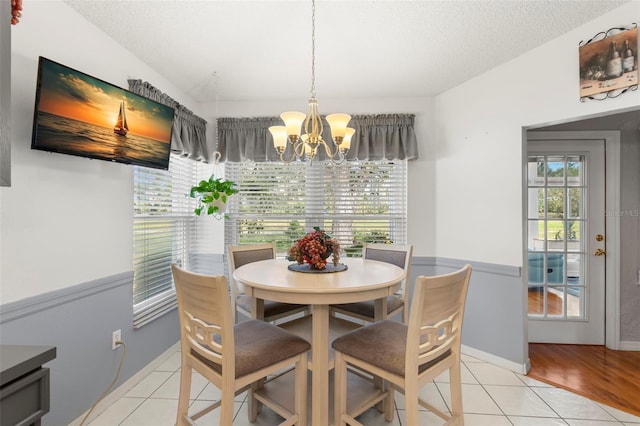 tiled dining room with an inviting chandelier and a textured ceiling