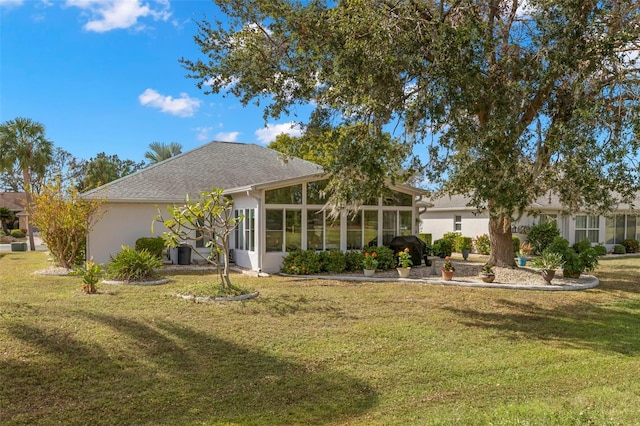 back of property featuring a sunroom and a lawn