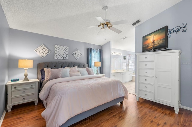 bedroom with connected bathroom, a textured ceiling, dark wood-type flooring, and ceiling fan