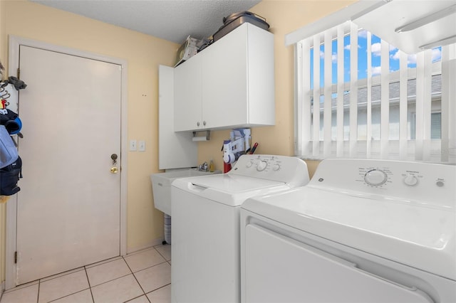 laundry room with cabinets, washer and dryer, a textured ceiling, light tile patterned flooring, and sink